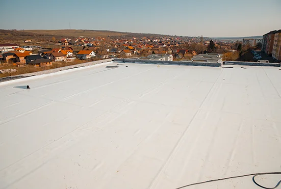 Flat white membrane roof on a low-slope building with neighborhood rooftops beyond