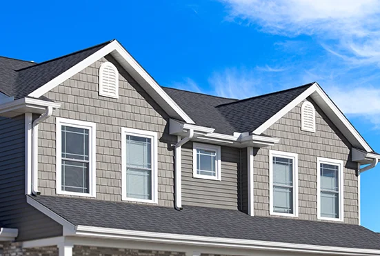Two-story house with gray siding, dormers and a dark asphalt shingle roof